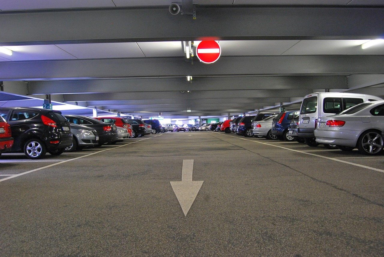 Estacionamiento de autos en garaje, señalización de sentido único y tráfico vehicular en carretera.