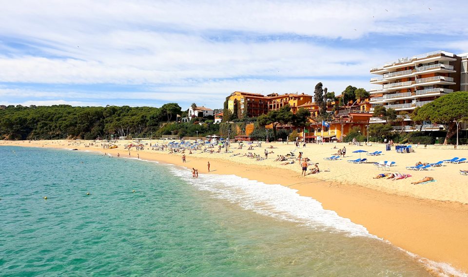 Platja de Fenals en Lloret de Mar con sus aguas tranquilas y pinos al fondo