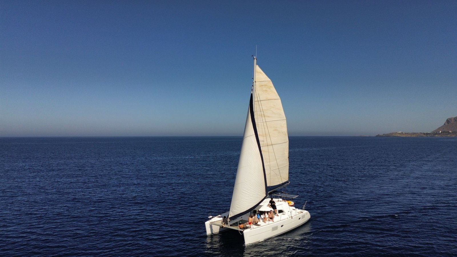 Catamar&aacute;n navegando en mar abierto bajo cielo despejado, aventura n&aacute;utica serena.