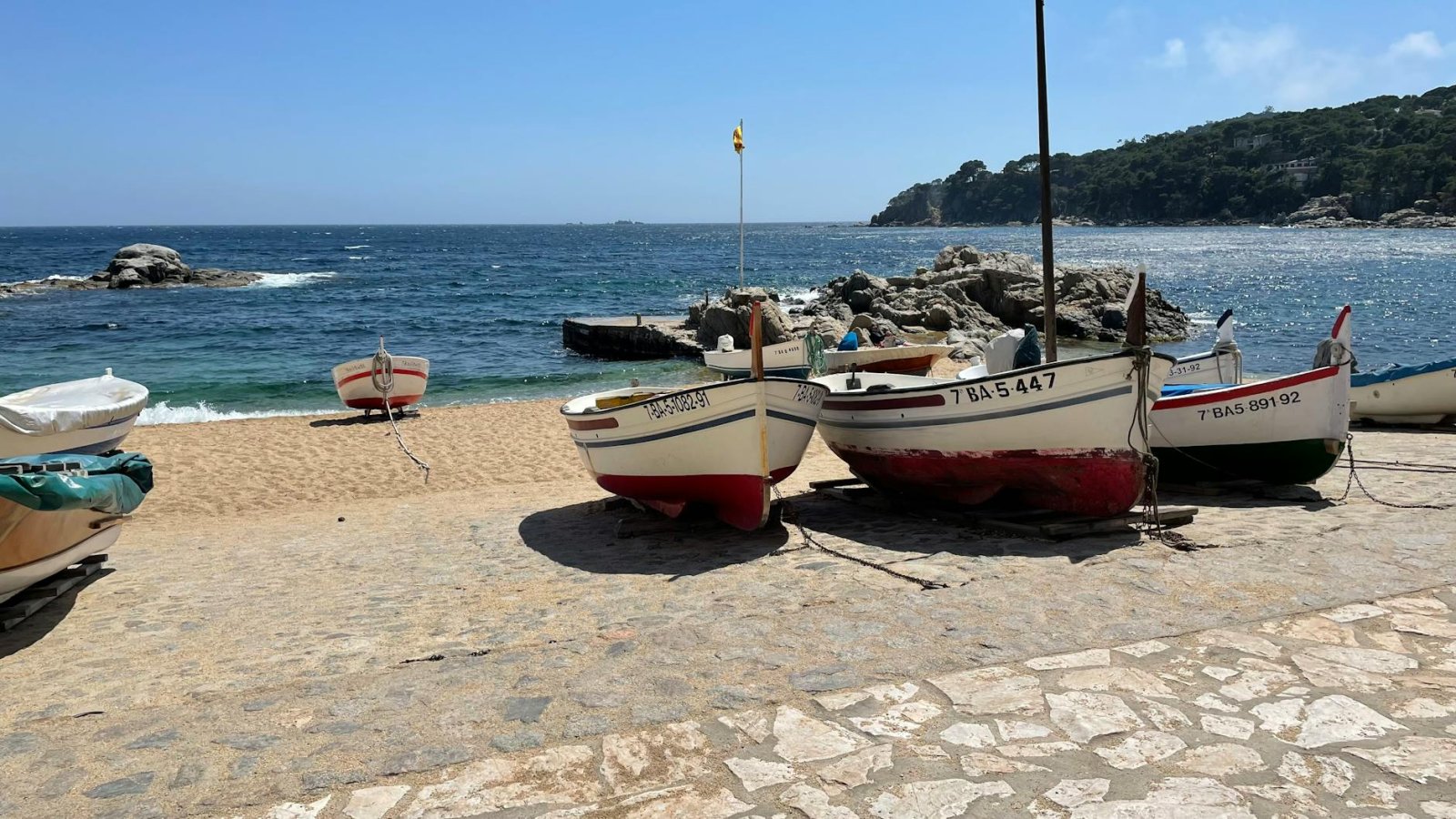A picturesque scene of colorful fishing boats resting on a sandy beach by the ocean.