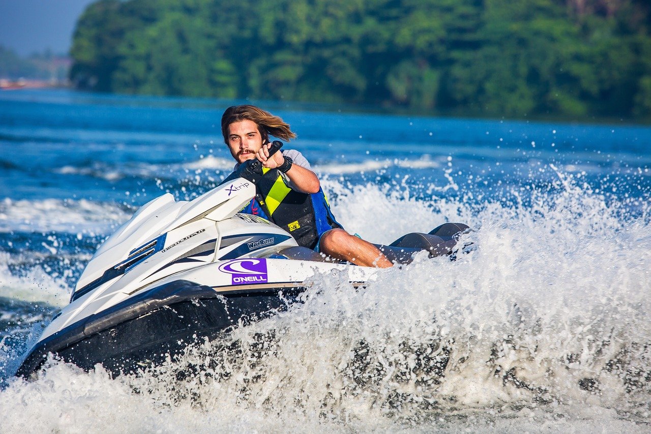 Hombre disfrutando de un jet ski salpicando en el mar, actividad de ocio y diversión.