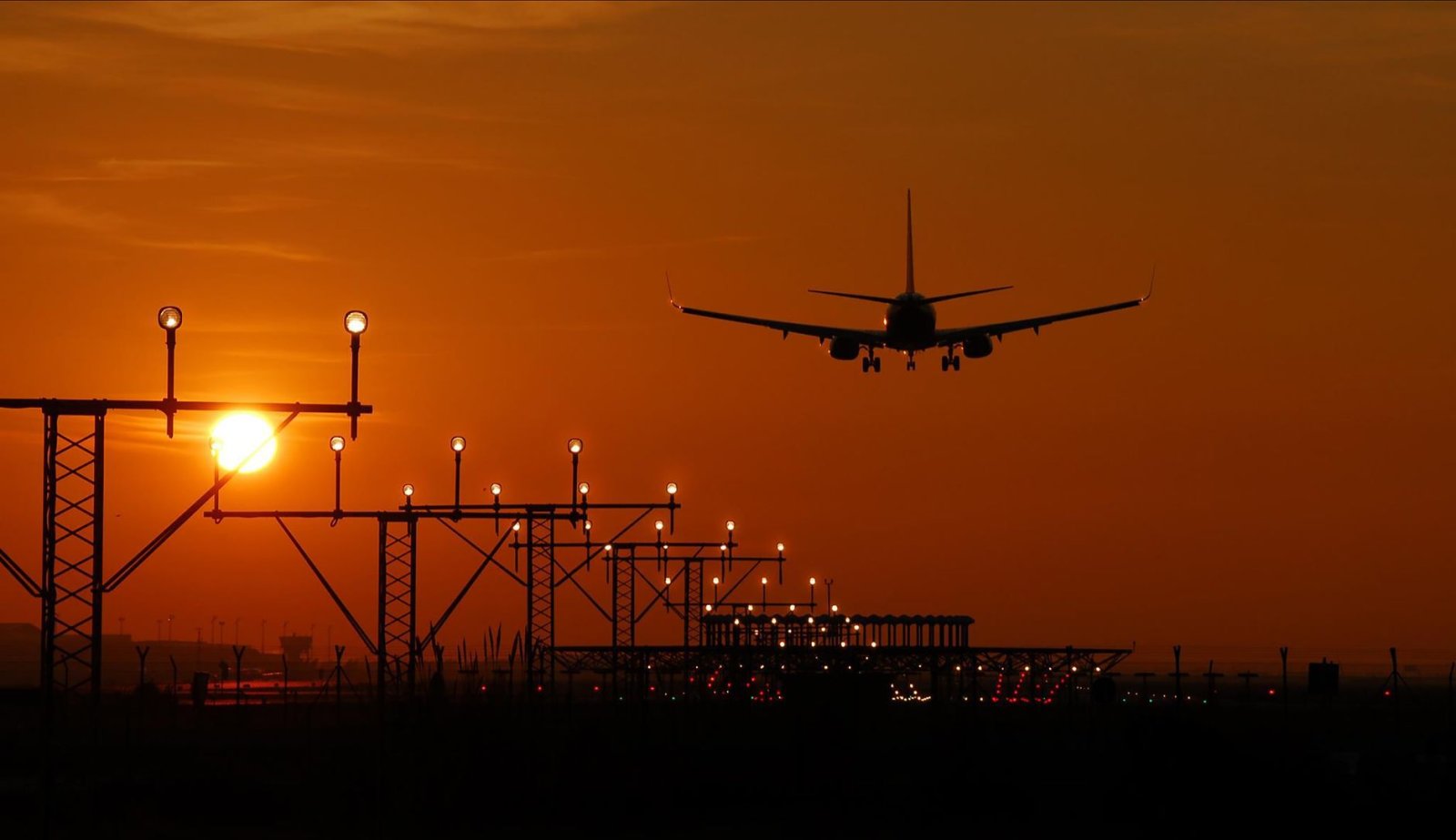 Flugzeug bei Sonnenuntergang in Barcelona, leuchtend oranger Himmel.