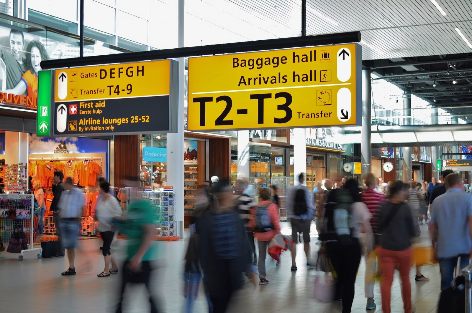 Belebter Flughafen, Bewegungsunschärfe, klare Ankunftsschilder und Gepäck.